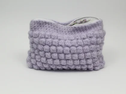 Beauty case crochet lilla, foderato in tessuto di cotone con motivo floreale.