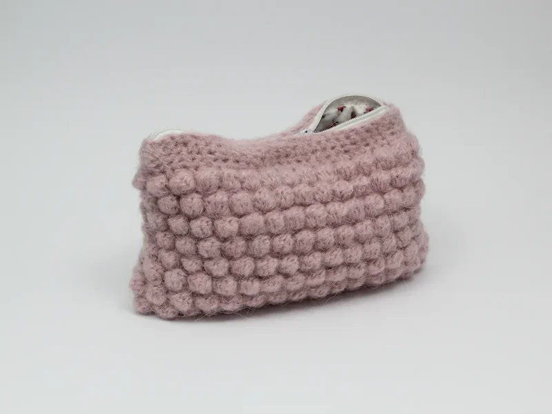 Beauty case crochet rosa baby, in lana baby alpaca, con cerniera bianca e foderato in tessuto di cotone a motivo floreale.