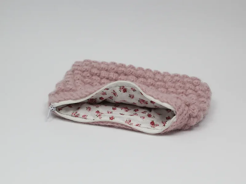 Beauty case crochet rosa baby, in lana baby alpaca, con cerniera bianca e foderato in tessuto di cotone a motivo floreale.