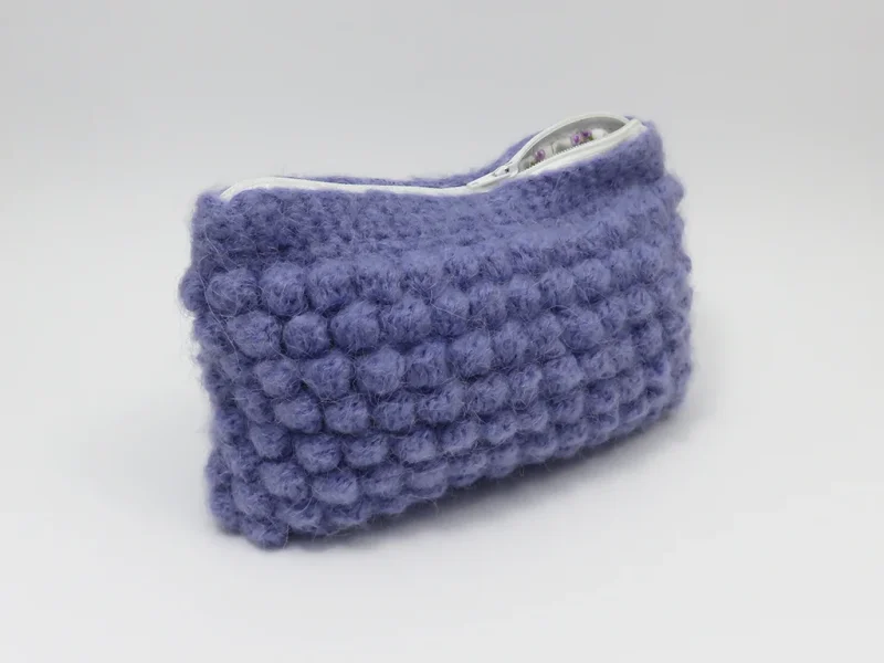 Beauty case crochet viola, foderato con tessuto di cotone con motivo floreale.