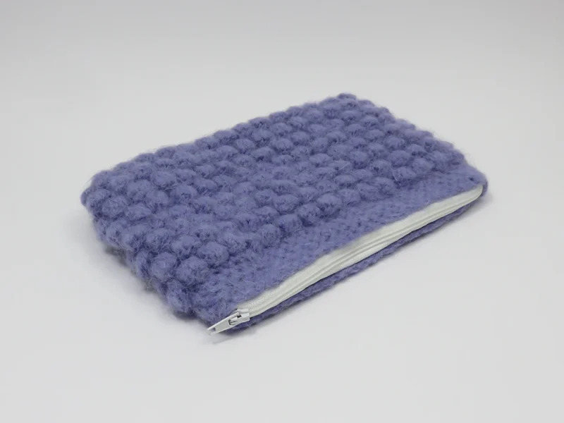 Beauty case crochet viola, foderato con tessuto di cotone con motivo floreale.