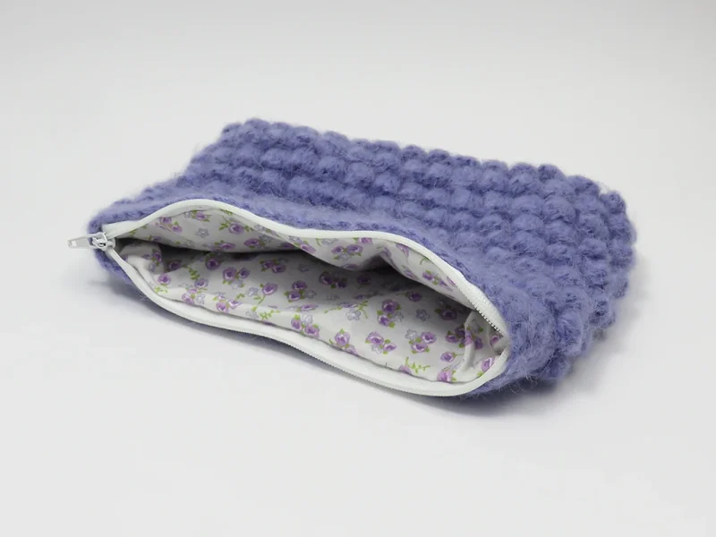 Beauty case crochet viola, foderato con tessuto di cotone con motivo floreale.