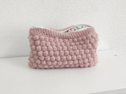 Beauty case crochet rosa baby, in lana baby alpaca, con cerniera bianca e foderato in tessuto di cotone a motivo floreale.