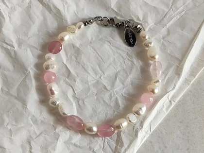 Bracciale in quarzo rosa, con perle di fiume bianche e chiusura a moschettone.