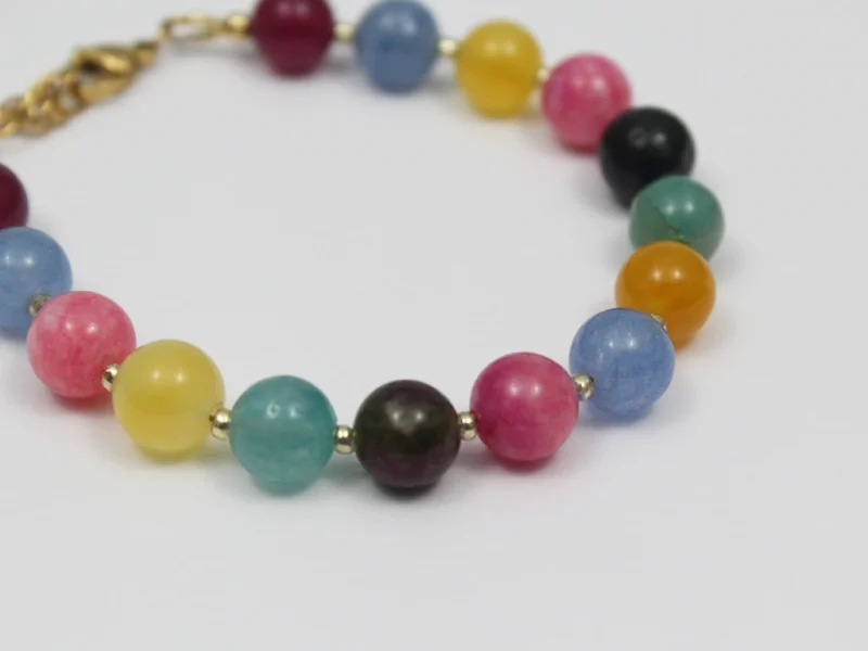 Bracciale con perle colorate, con chiusura a moschettone e catenella di estensione dorata.