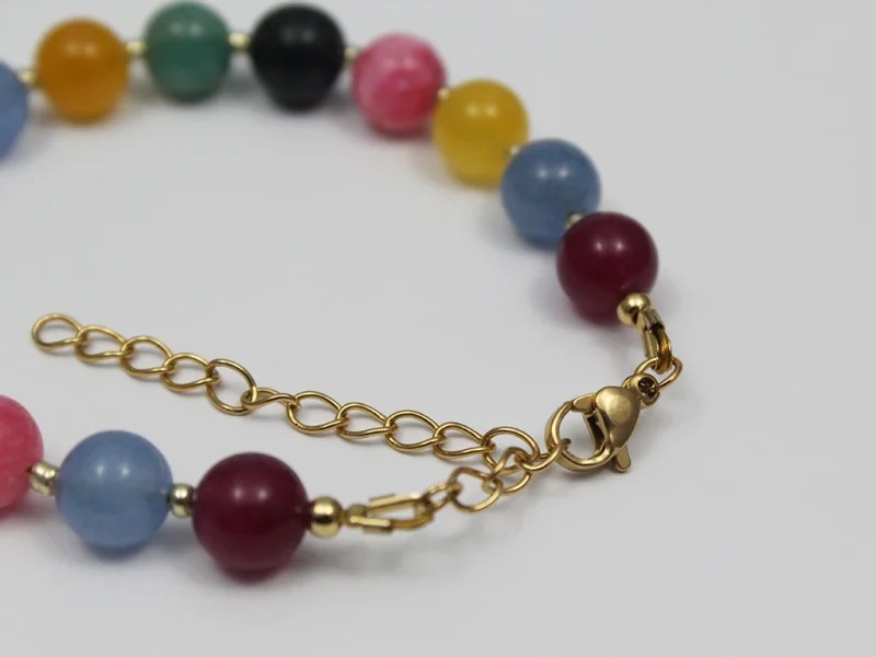 Bracciale con perle colorate miste, con chiusura a moschettone e catenella di estensione dorata.