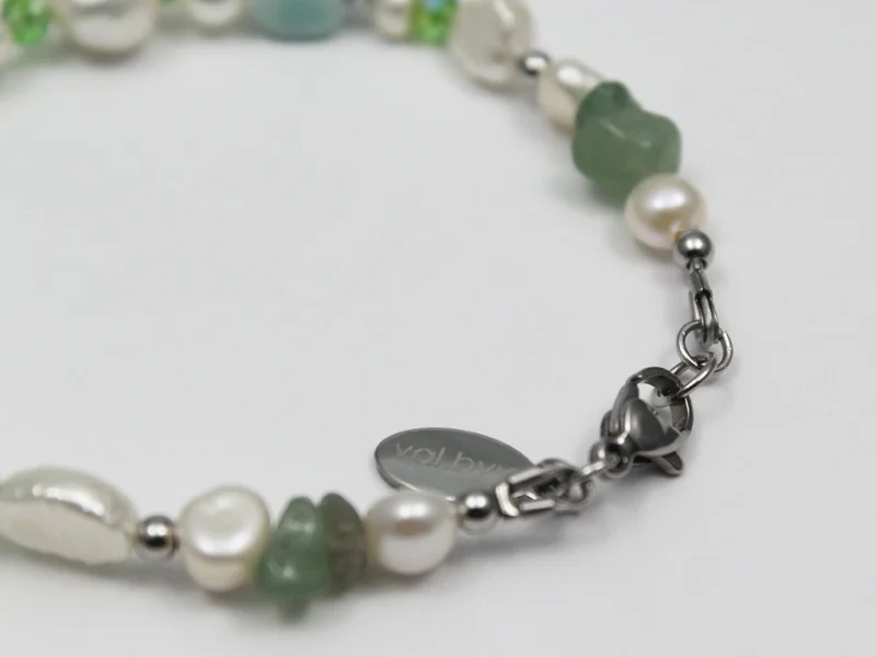 Bracciale di perle e pietre verdi, con chiusura a moschettone.