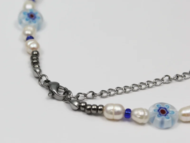 Collana in vetro murano blu, con perle di fiume irregolari e perline in vetro, con chiusura a moschettone e catenella di estensione.