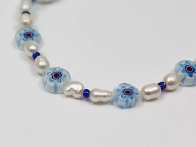 Collana in vetro murano blu, con perle di fiume irregolari e perline in vetro, con chiusura a moschettone e catenella di estensione.