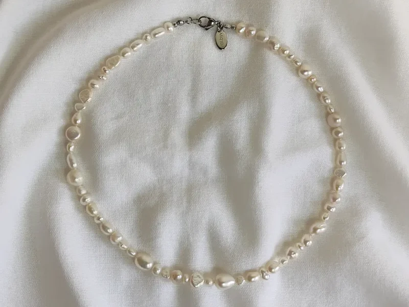 Collana di perle di fiume miste, di varie forme e dimensioni irregolari, con chiusura a moschettone.