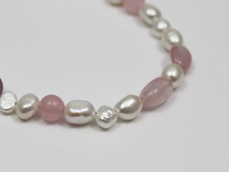 Bracciale in quarzo rosa, con perle di fiume bianche e chiusura a moschettone.