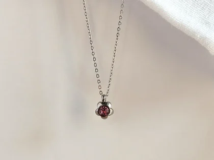 Collana con ciondolo a fiore rosa, con catenella fine in acciaio inox e chiusura a moschettone.