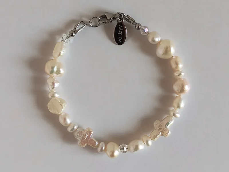 Bracciale di perle con croci, indossato.