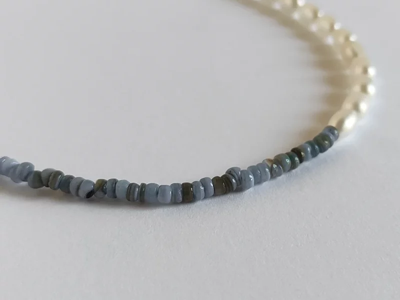 Collana metà perle e metà madreperla blu, con chiusura a moschettone dorata in acciaio inox e ciondolo a forma di cuore finale.