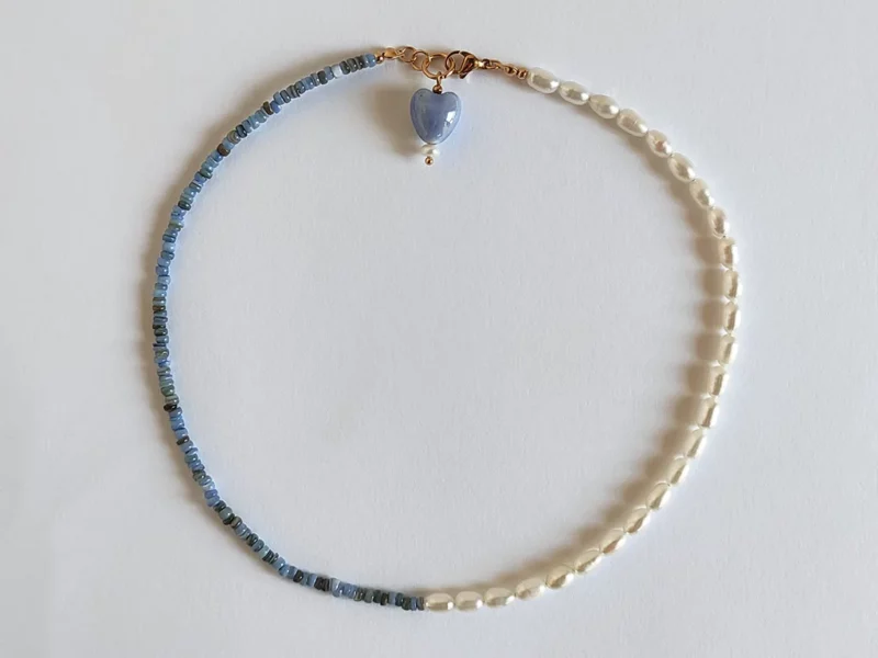 Collana metà perle e metà madreperla blu, con chiusura a moschettone dorata in acciaio inox e ciondolo a forma di cuore finale.