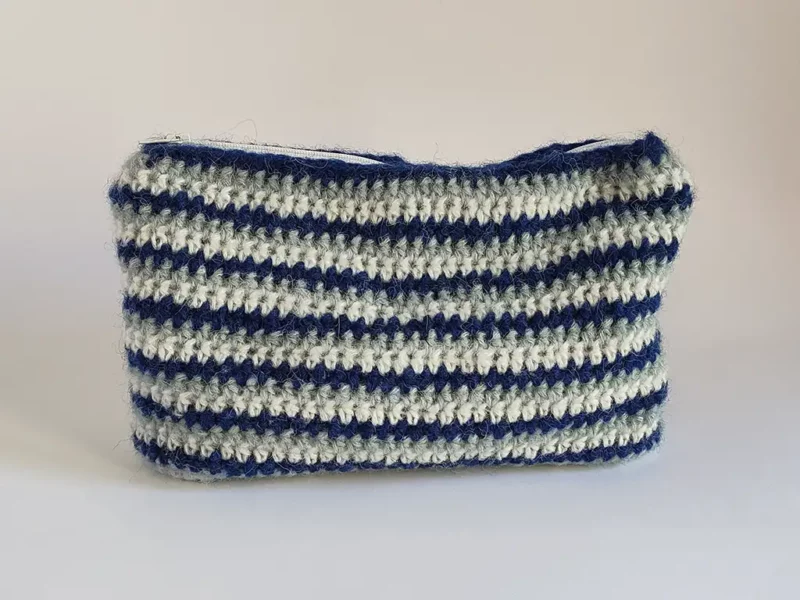 Beauty case crochet a righe blu, in lana di baby alpaca, foderata in cotone e con cerniera a zip.