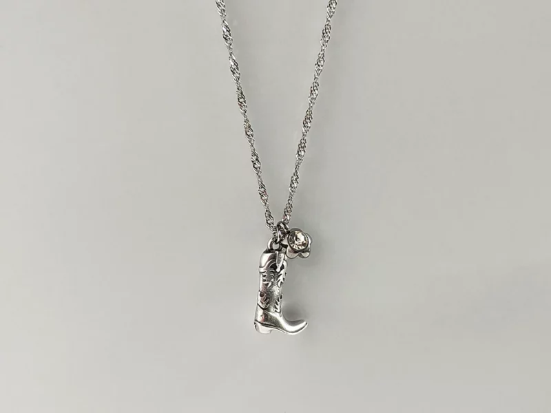 Collana "cowgirl", con ciondolo a forma di stivale da Cowboy argentato e fiore con brillante bianco centrale, con catenella in acciaio inox.